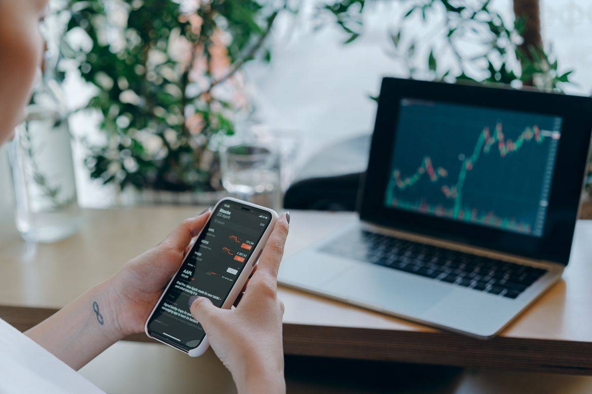 Kanak Capital Markets review showing mobile and desktop trading platforms with rising market charts.
